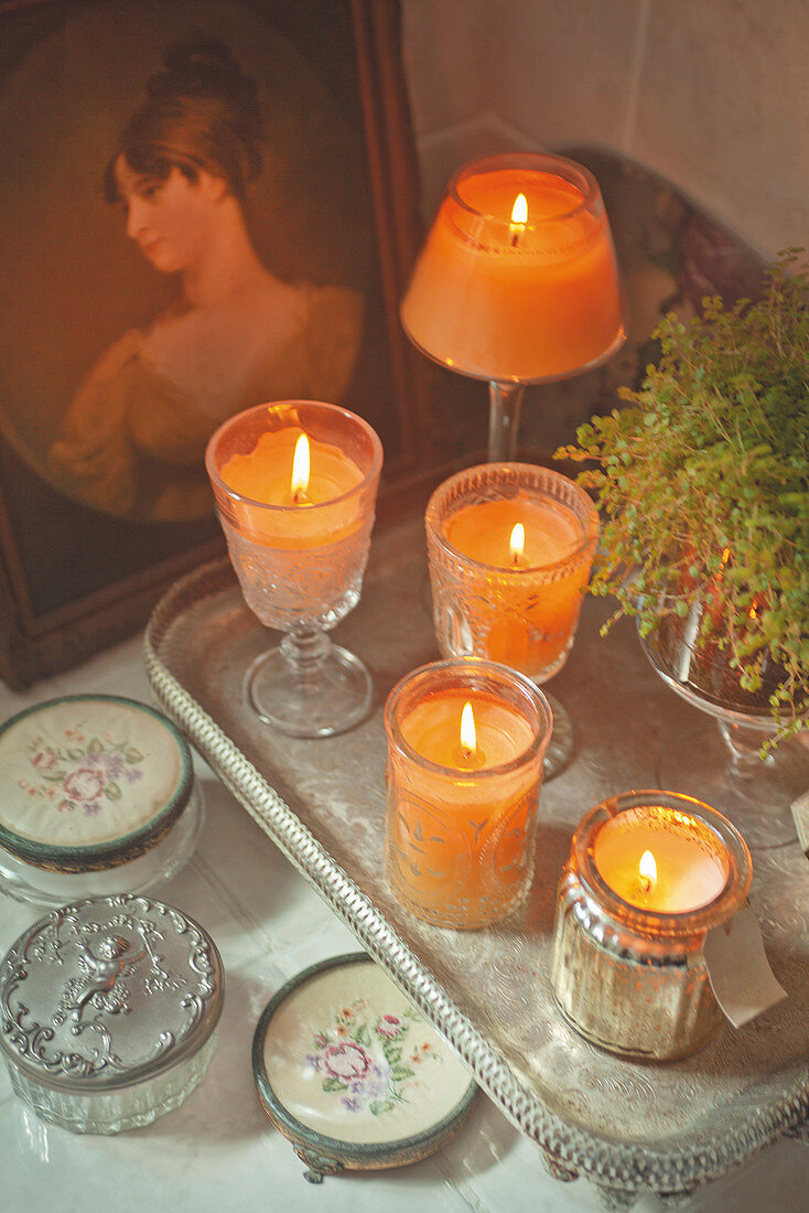 Arrangement of candles in vintage glass holders on silver tray