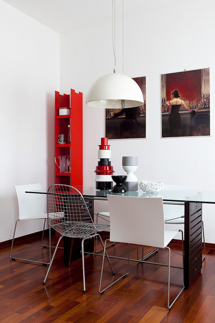 Zimmerecke mit schmalem roten Wandregal und Esstisch aus Glas