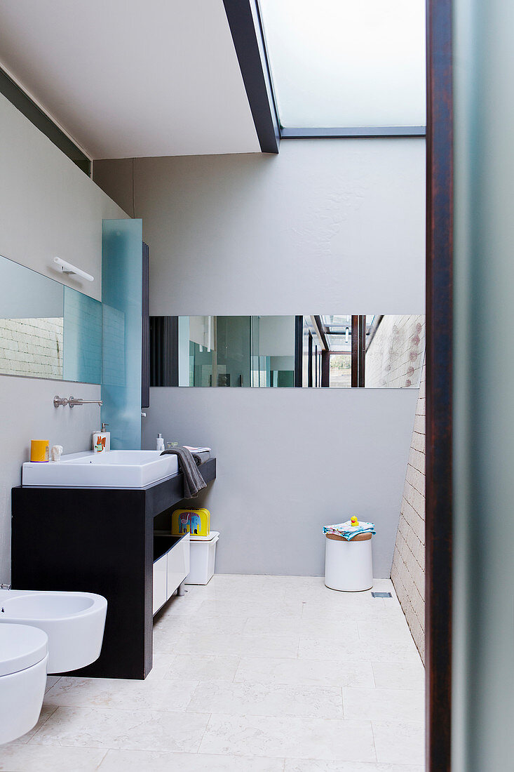 Minimalistisches Bad in Architektenhaus mit Oberlicht und waagerecht verlaufendem Spiegelband
