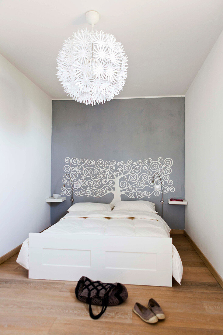 White bed and tree of life motif on grey wall in minimalist bedroom