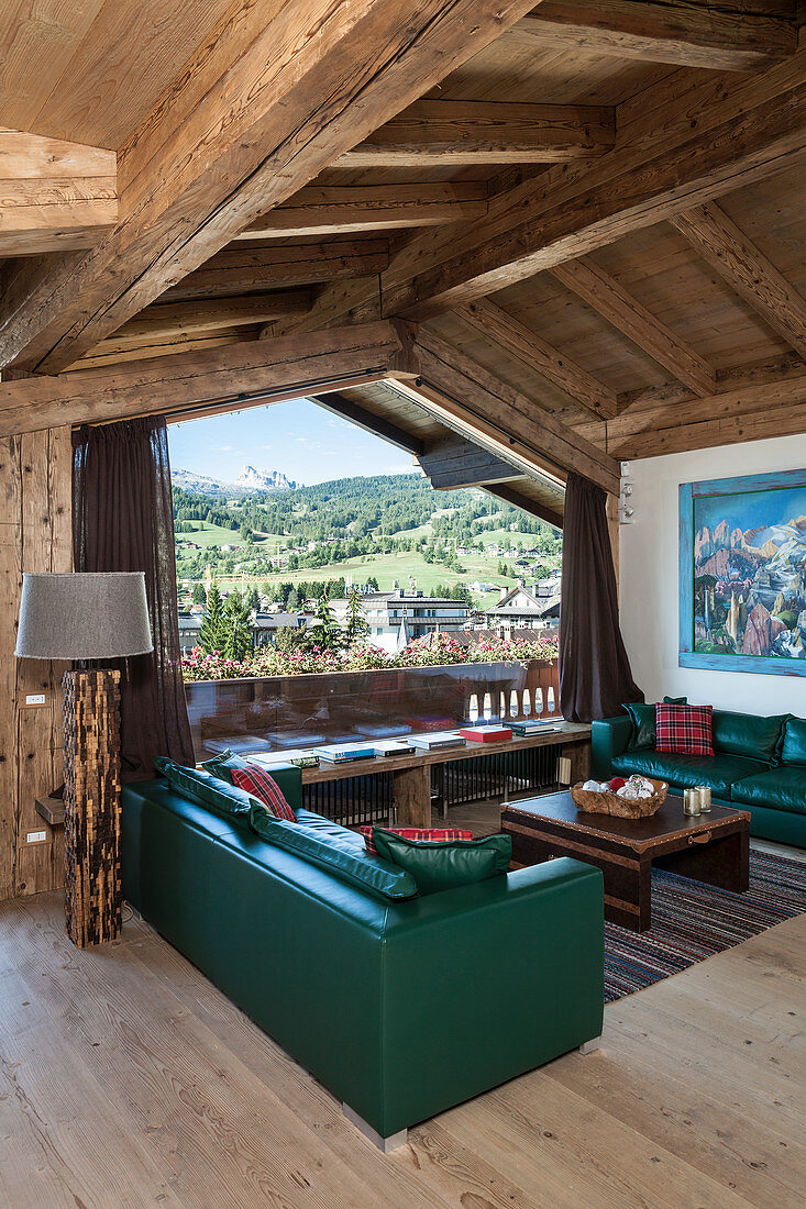 Green leather sofas in living room of rustic wooden house