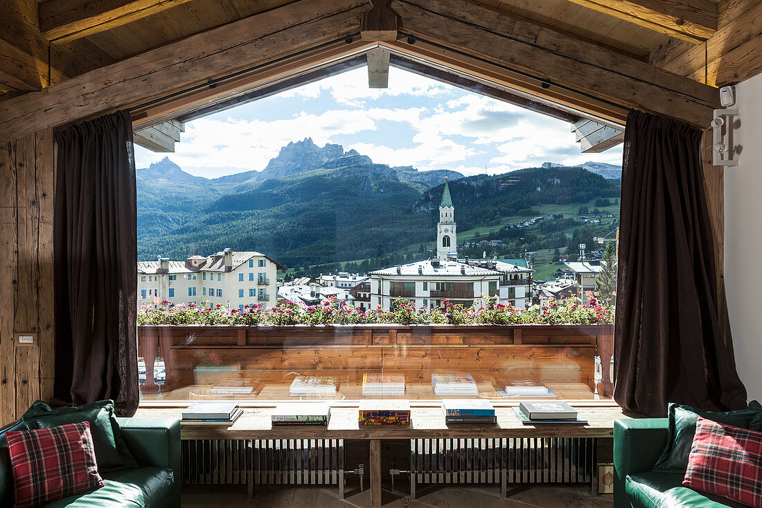 Blick aus dem Panoramafenster eines Chalets aufs Bergdorf
