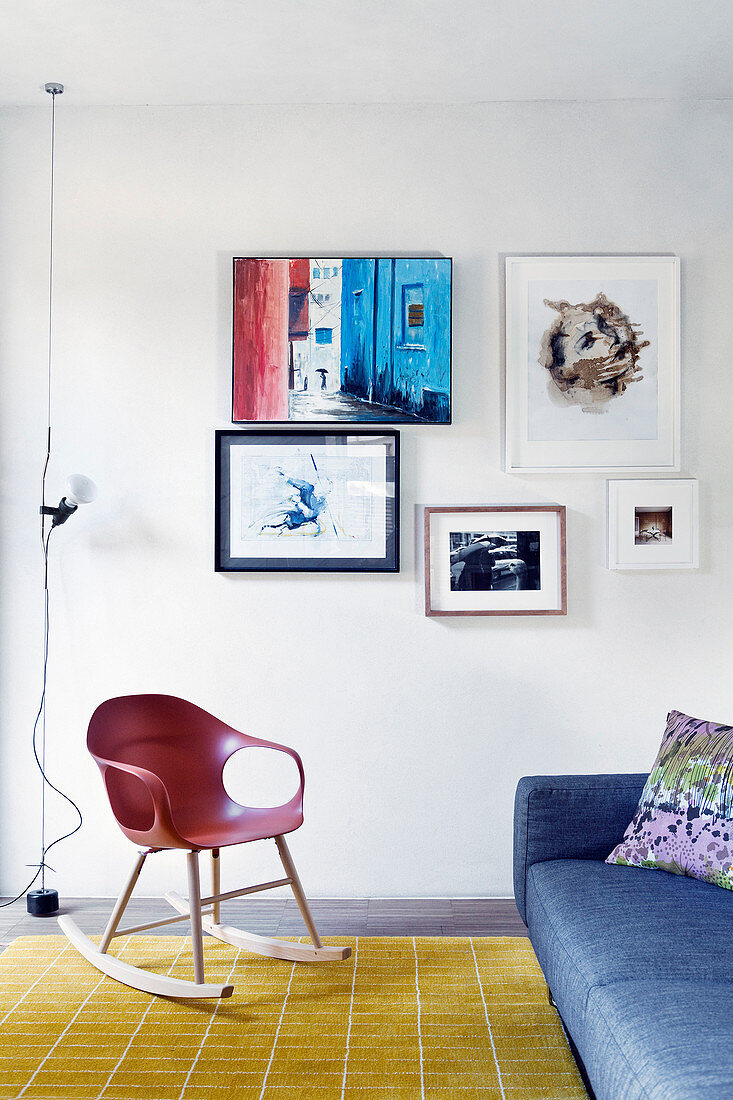 Sitzbereich vor Bilderwand mit Designer-Schaukelstuhl und Couch