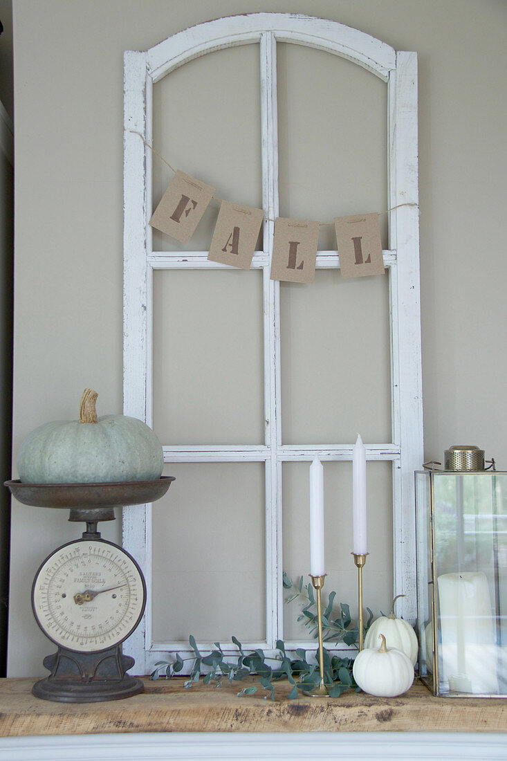 Ornamental window frame, ornamental squash on vintage kitchen scales, and candles on mantelpiece