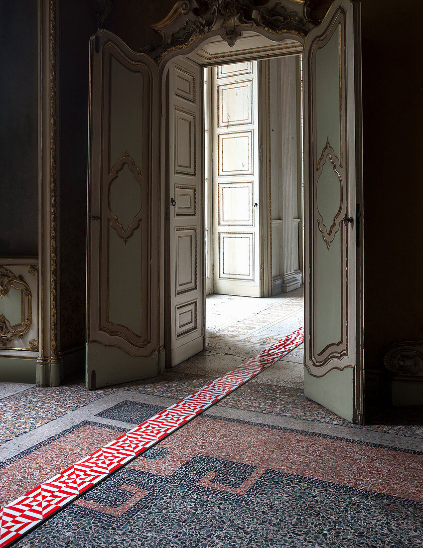 Moderne rot-weiß gemusterte Fliesen als Streifen ausgelegt auf antikem Mosaikboden