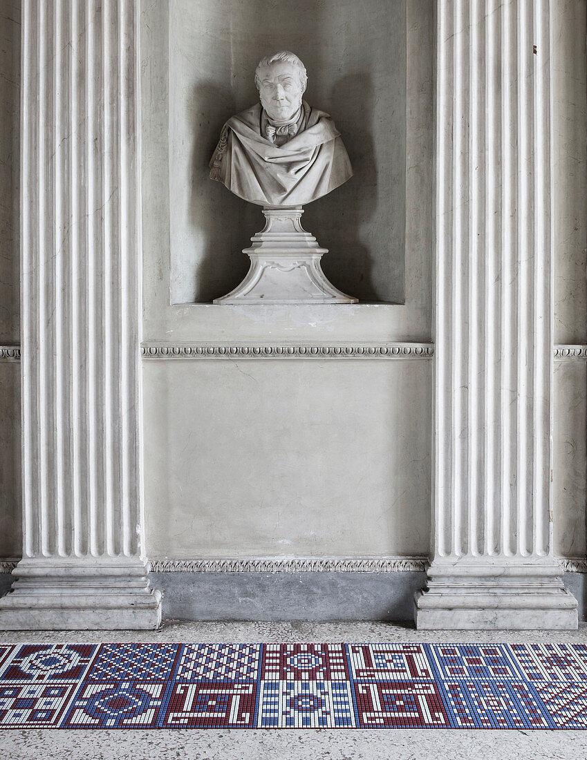 Modern, geometric tiles below antique bust flanked by columns