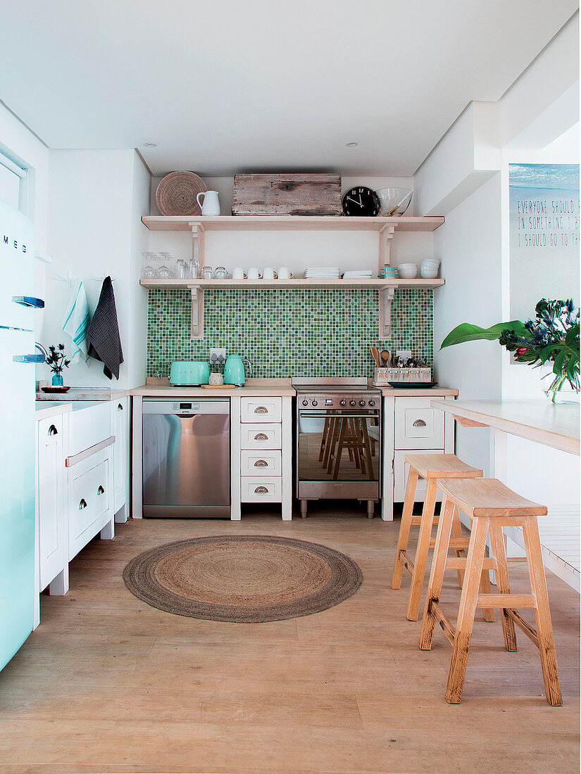 Lichtdurchflutete Küche mit blaugrünem Mosaikfliesenspiegel und weißen Küchenschränken