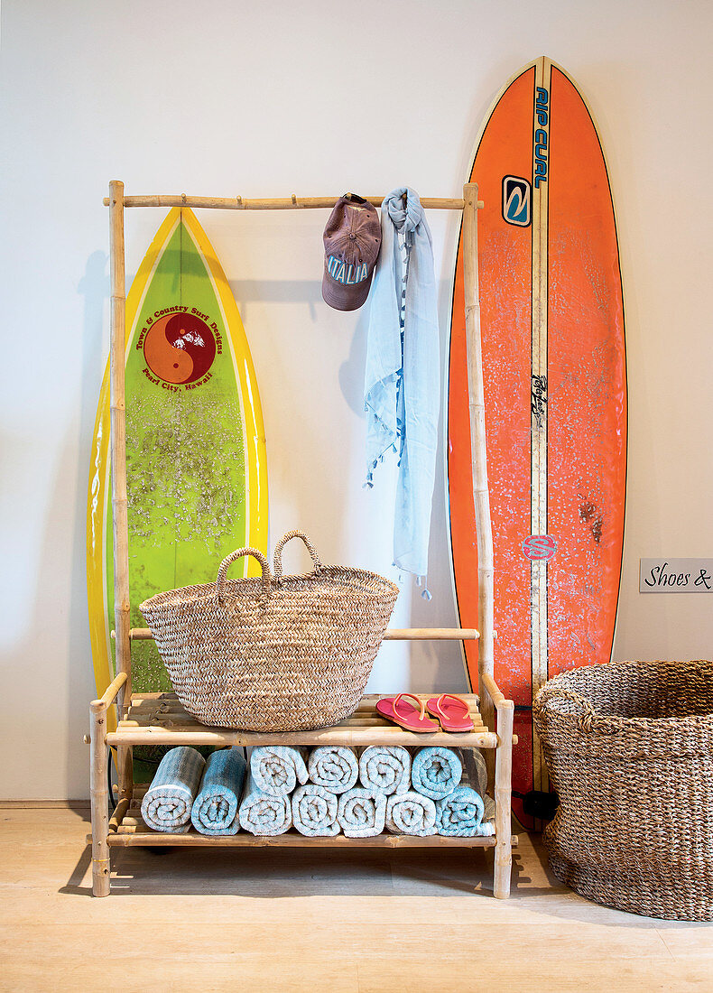 Surfboards stored behind coat rack made from bamboo poles