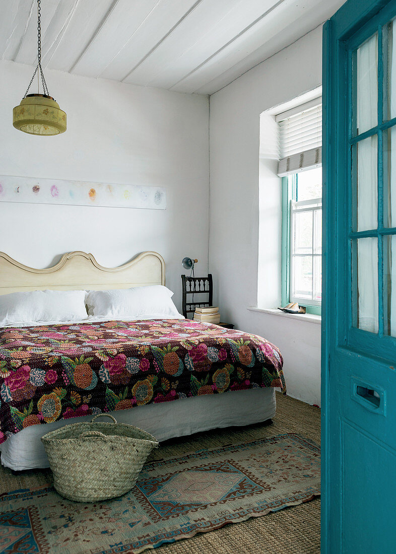 Geöffnete blaue Tür zum Gästezimmer mit Bett und dekorativenm handgemachten Quilt