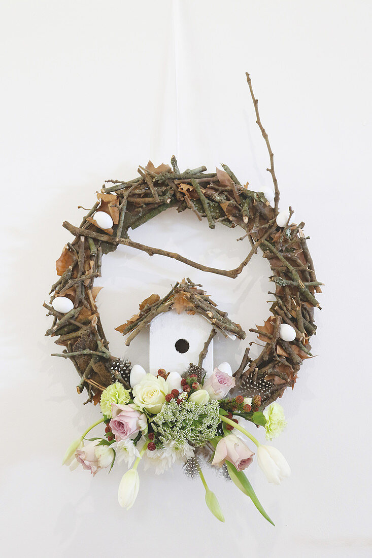 Wreath decorated with twigs, spring flowers and ornamental bird box