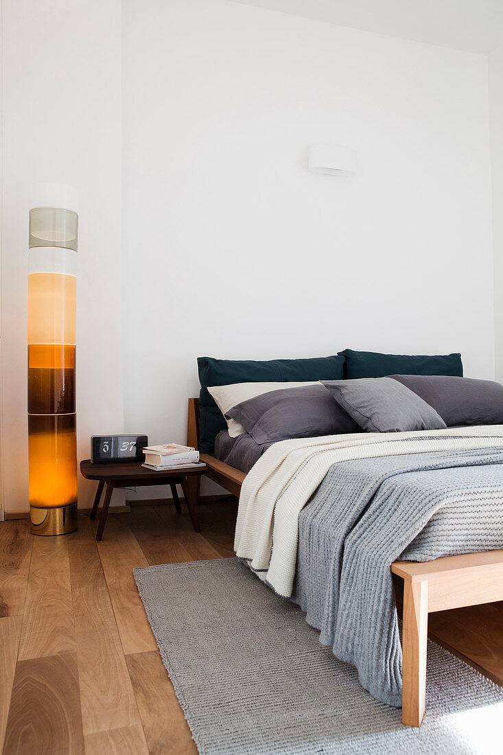 Dekorative Säulen-Wasserlampe neben Holzbett in Schlafzimmer