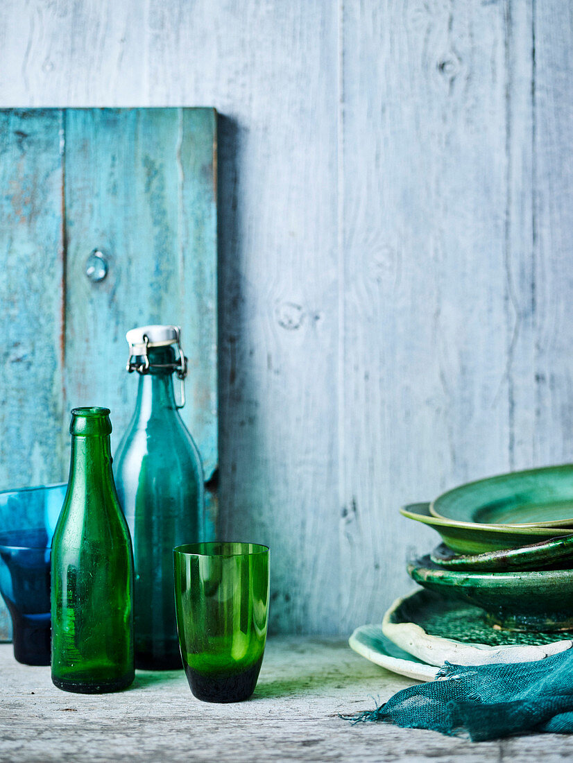 Still life with green and blue plates, glasses and bottles