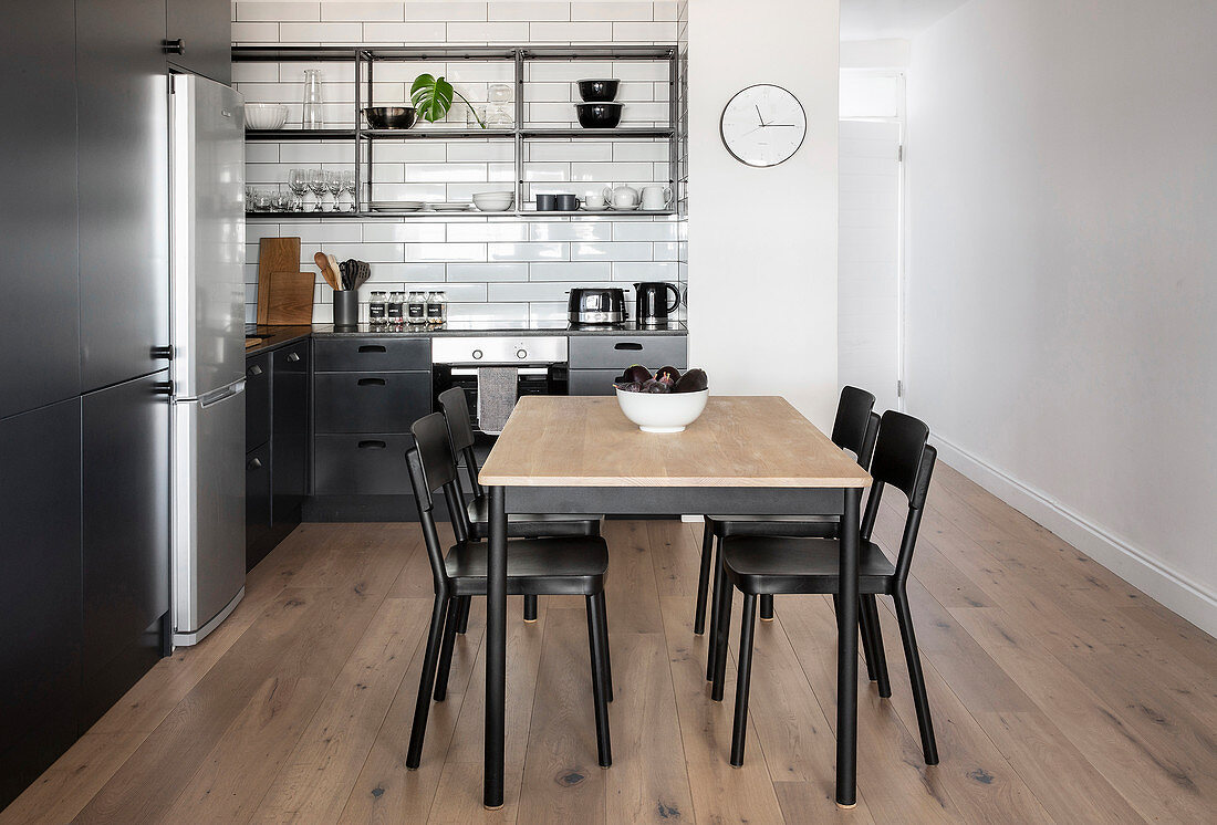 Küchenbereich in Apartment mit Esstisch und offenen Regalen über schwarzer Küchenzeile