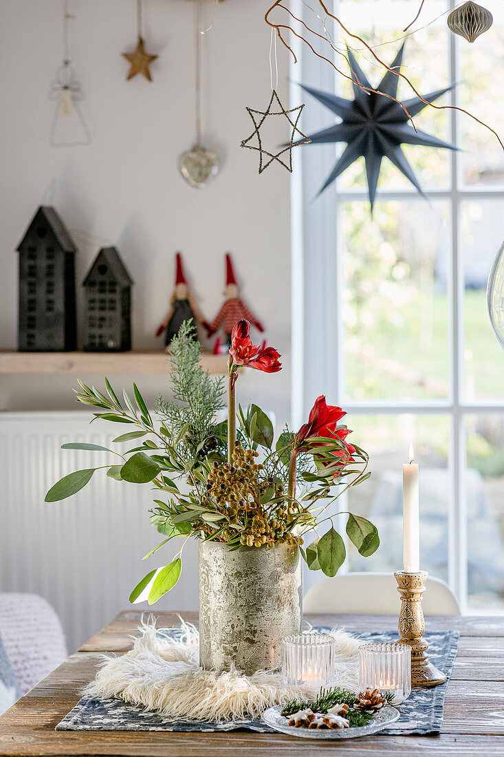 Winterlicher Strauß mit Zweigen und Amaryllis auf dem Tisch am Fenster