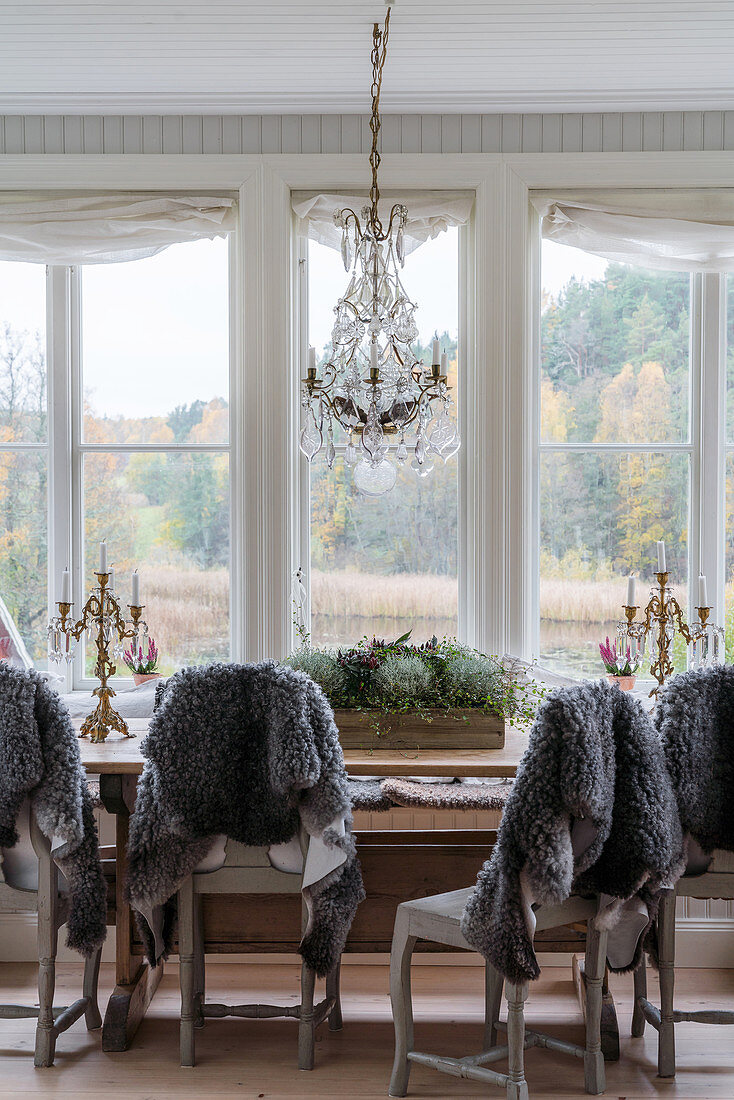 Graue Schaffelle über den Stühlen am Esstisch im Wintergarten