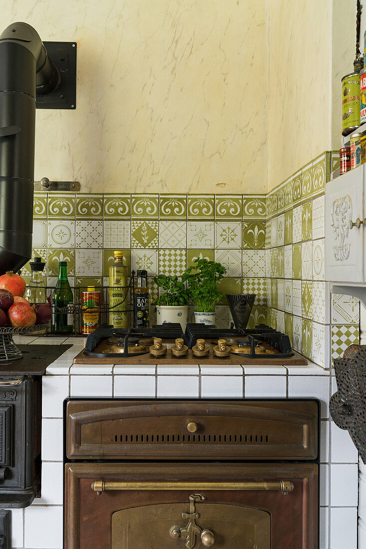 Gas hob and oven in rustic kitchen with green tiles