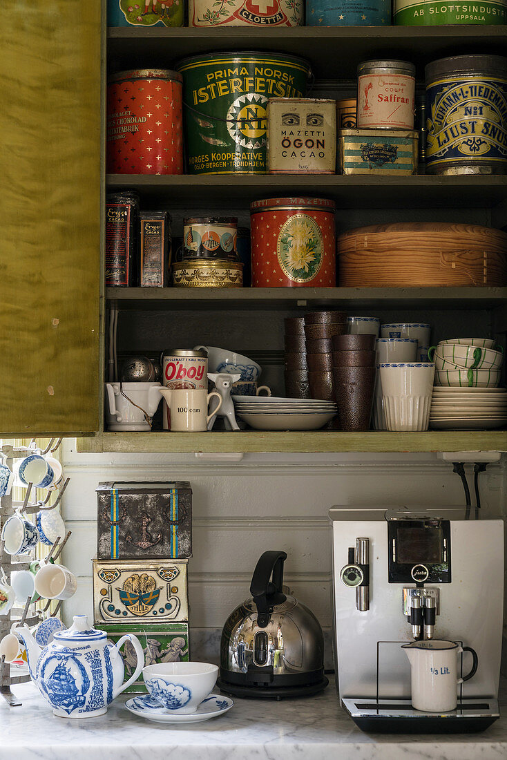 Alte Blechdosen und Geschirr im Küchenschrank über Kaffeeautomat