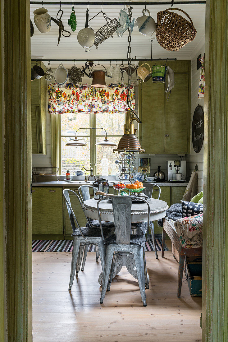 Metal chairs around pedestal table in green, retro-style kitchen-dining room