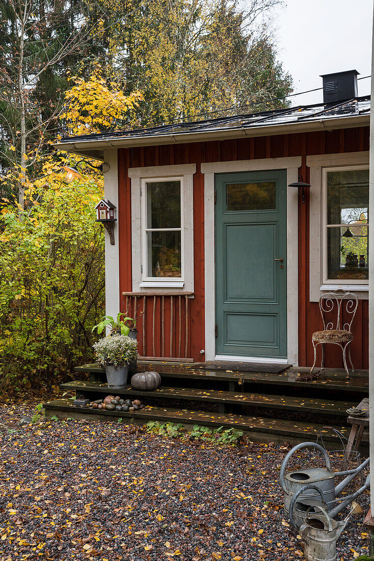 Rotes Schwedenhaus mit graublauer Tür im herbstlichen Garten