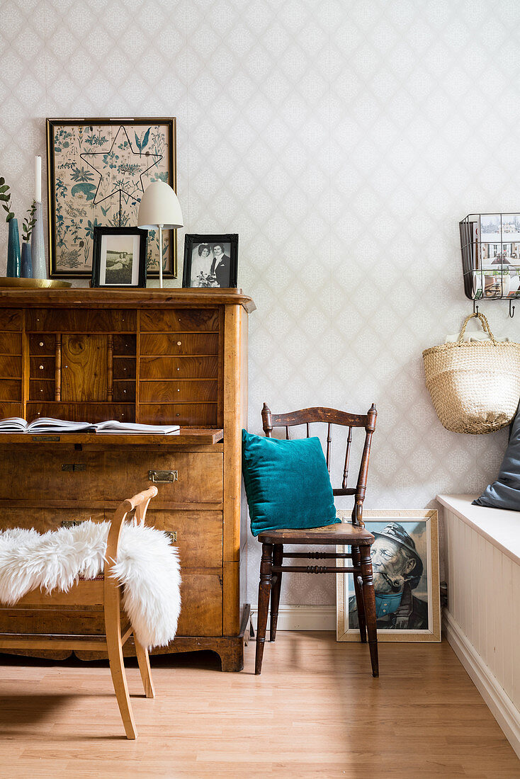 Old chair and antique bureau against diamond-patterned wallpaper