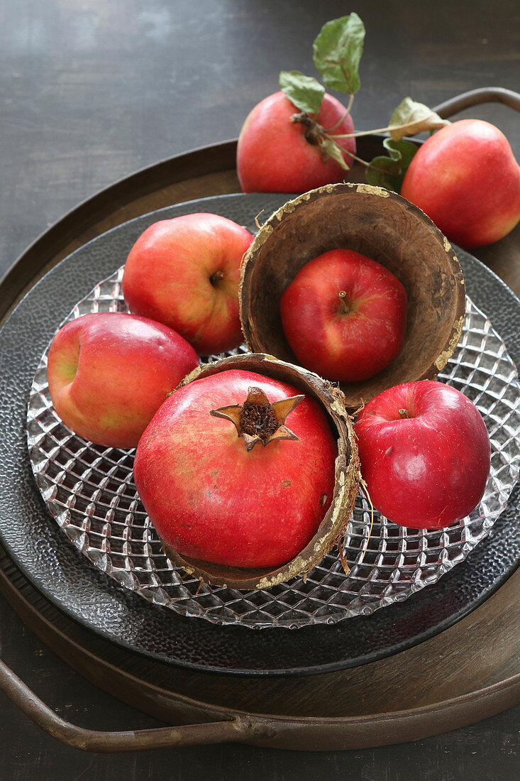 Rote Äpfel und Granatapfel als Herbstdekoration auf Teller