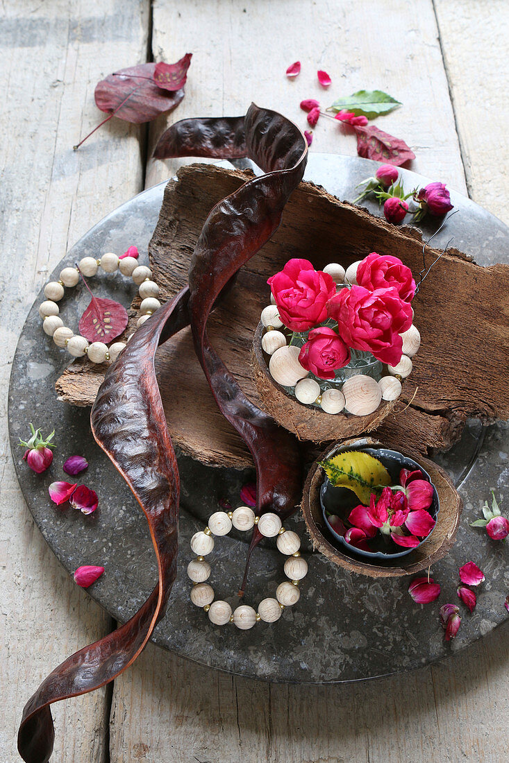 Autumnal arrangement of tree bark, roses, wooden beads and carob pods