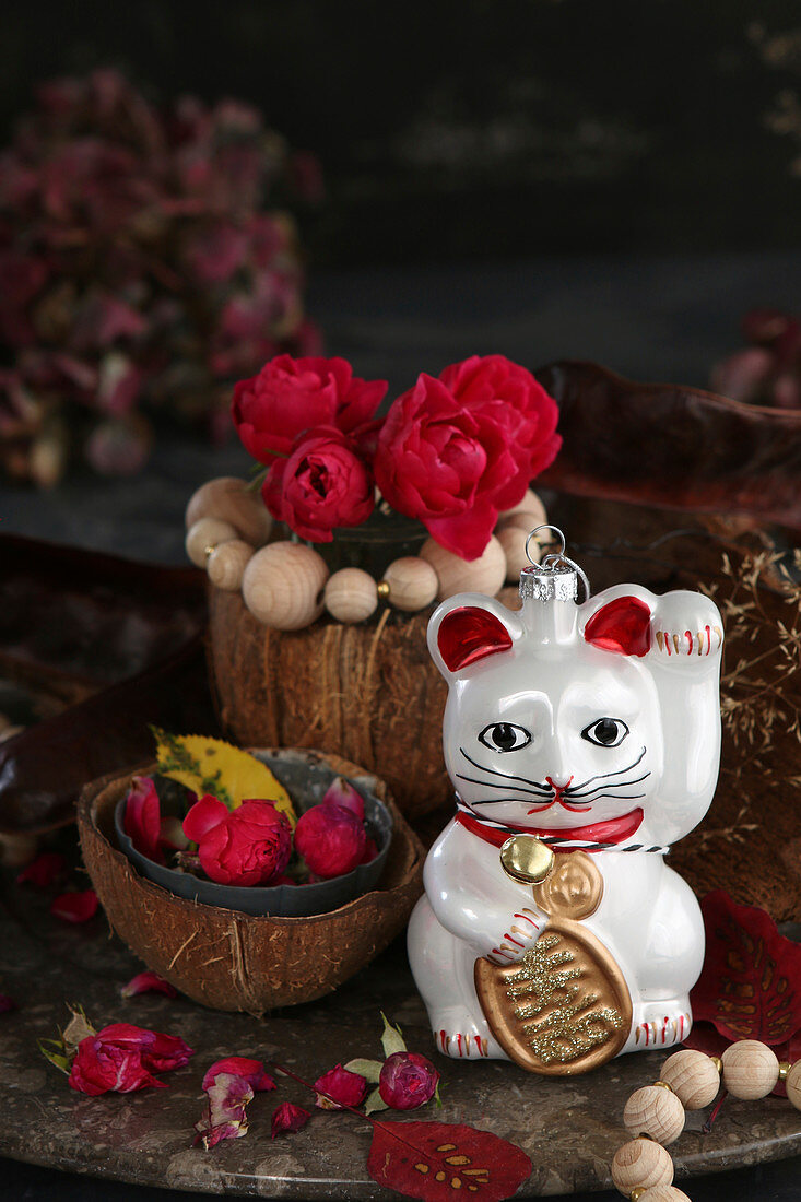 Arrangement of Maneki-neko cat and red roses in coconut shell