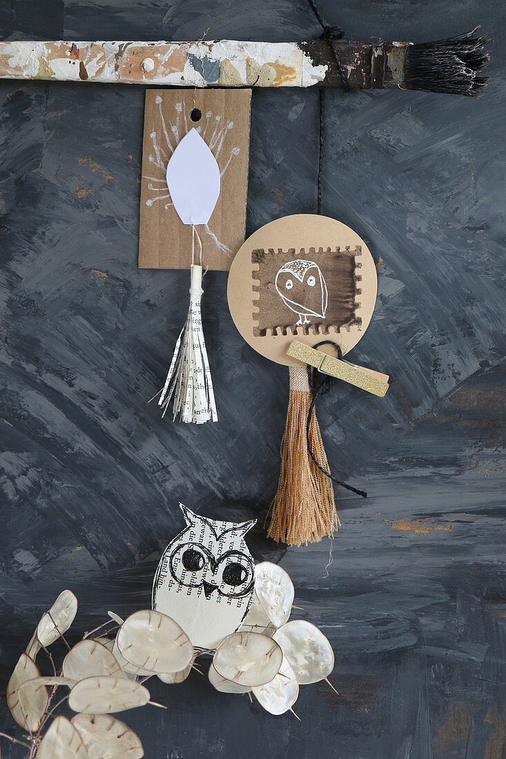 Handmade mobile of tassels, paper pendants, owls and sprig of honesty