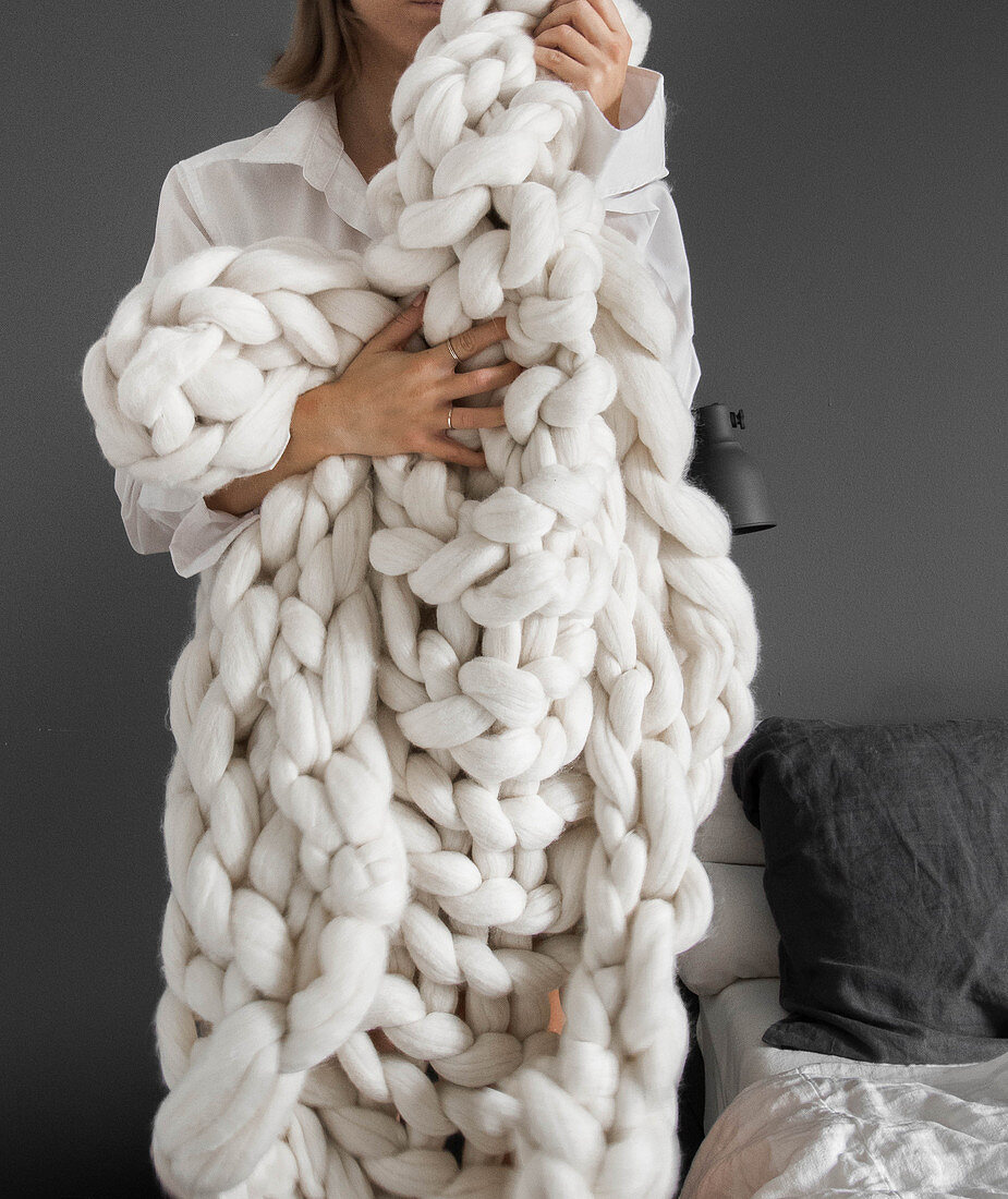 Woman holding chunky knitted blanket