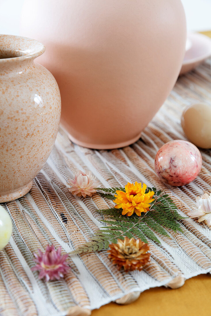 Vasen, Ostereier, Strohblumen und Farnblatt als Tischdeko zu Ostern