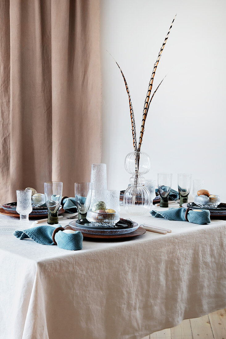 Gedeckter Tisch in Blau und Naturtönen mit Fasanenfedern