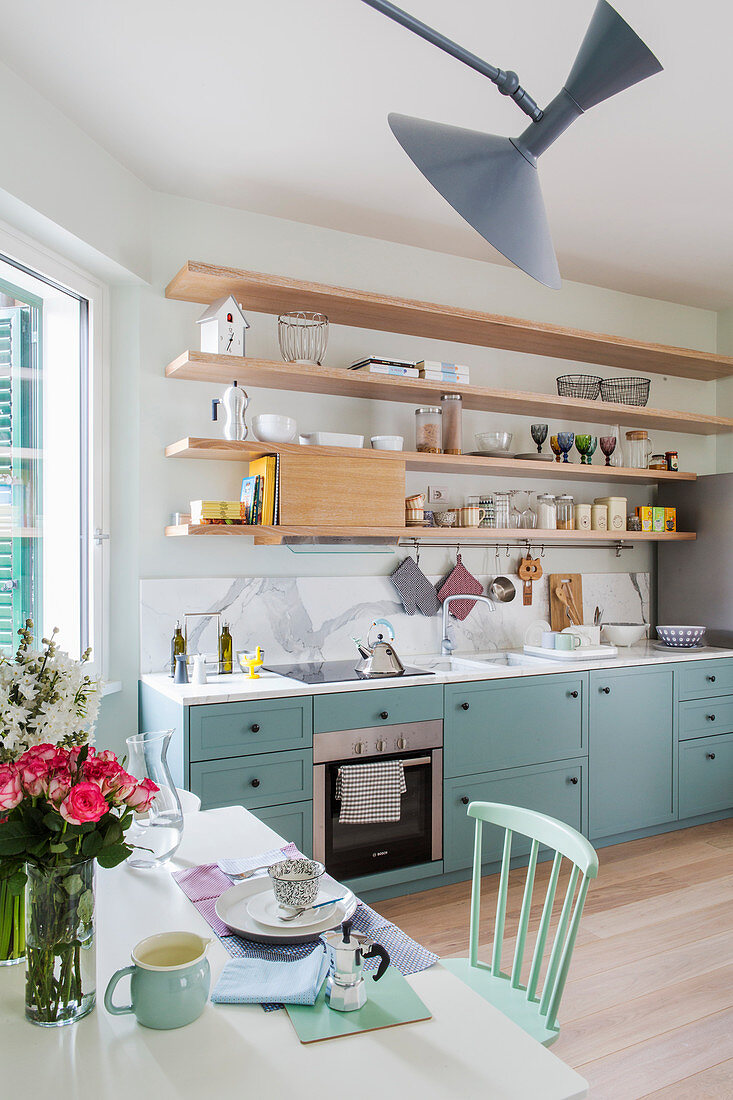 Küchenzeile mit blauen Holzfronten und offenen Regalen für Küchenutensilien