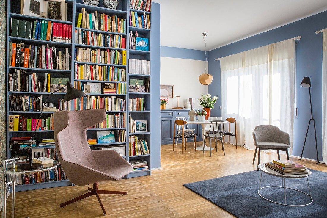 Blue interior with floor-to-ceiling bookcase and dining and seating areas