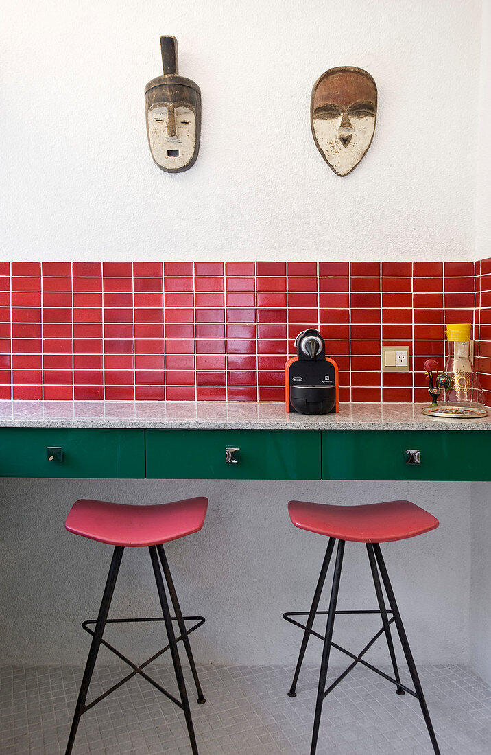 Bar stools under counter in retro red-and-green kitchen