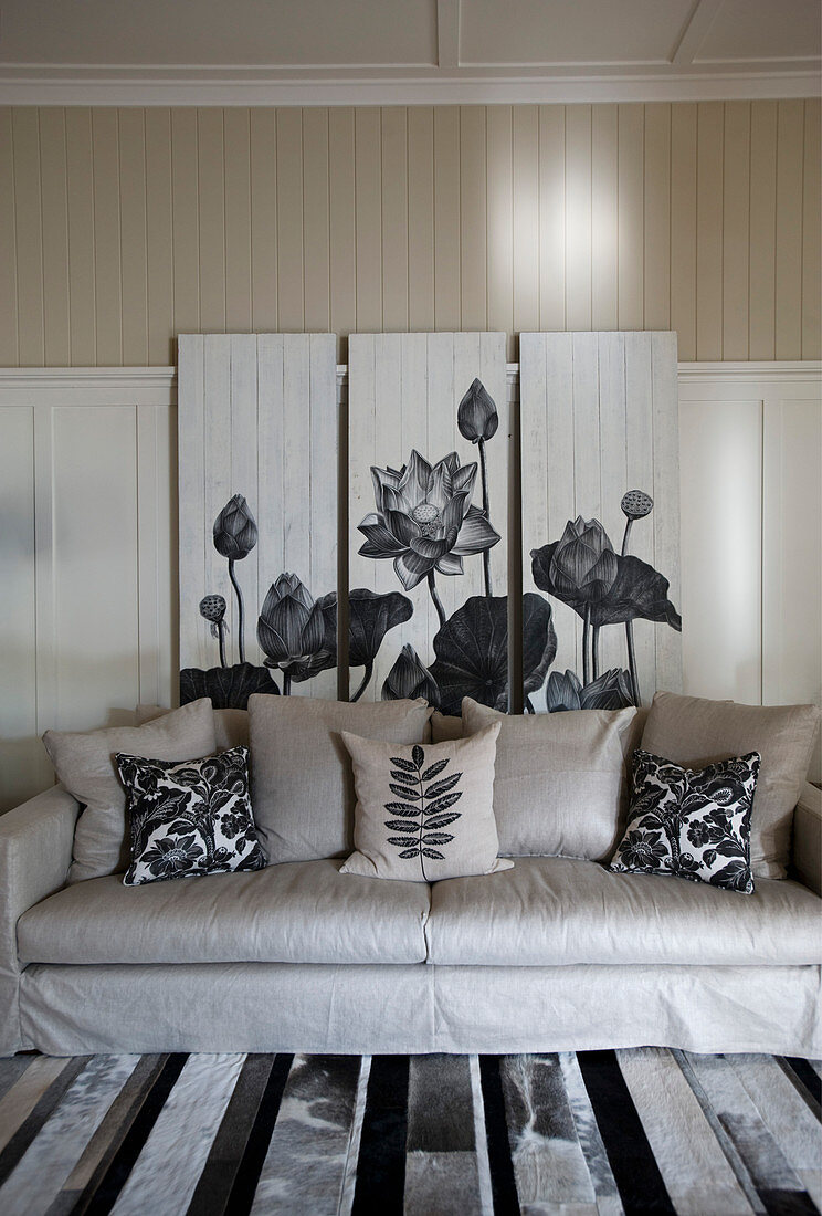 Triptychon mit Blumenmotiv hinterm Sofa im Wohnzimmer in Grautönen