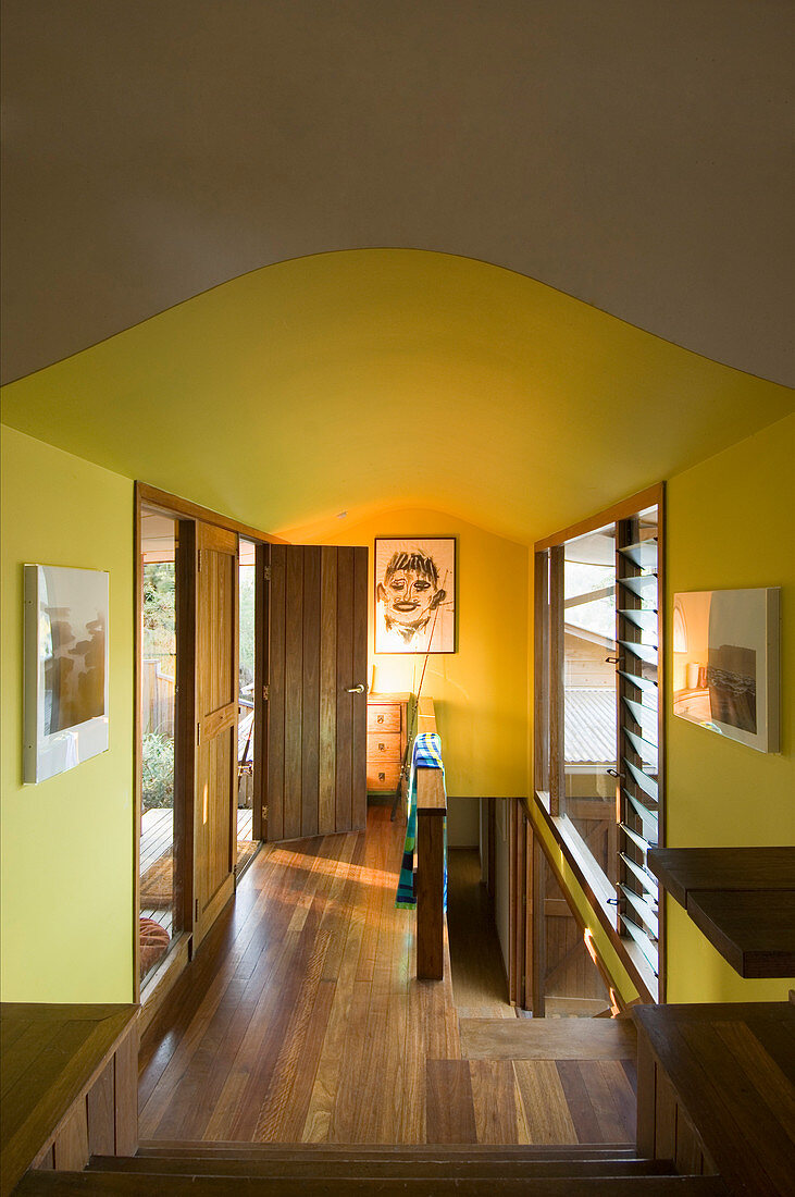 Gelber Flurbereich mit Eichentüren, Eichenböden sowie Treppenabgang zum Untergeschoss