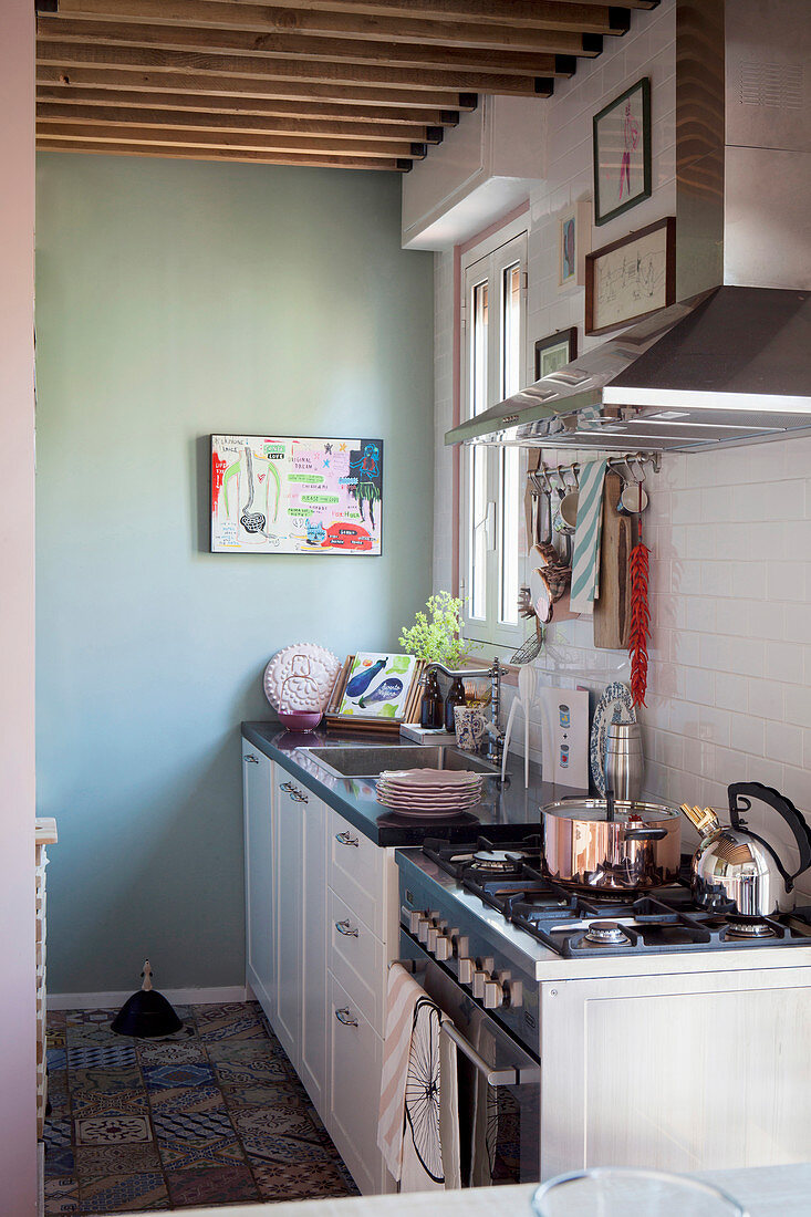 Küchenbereich mit mintgrüner Wand, weißer Küchenzeile und Musterfliesenboden