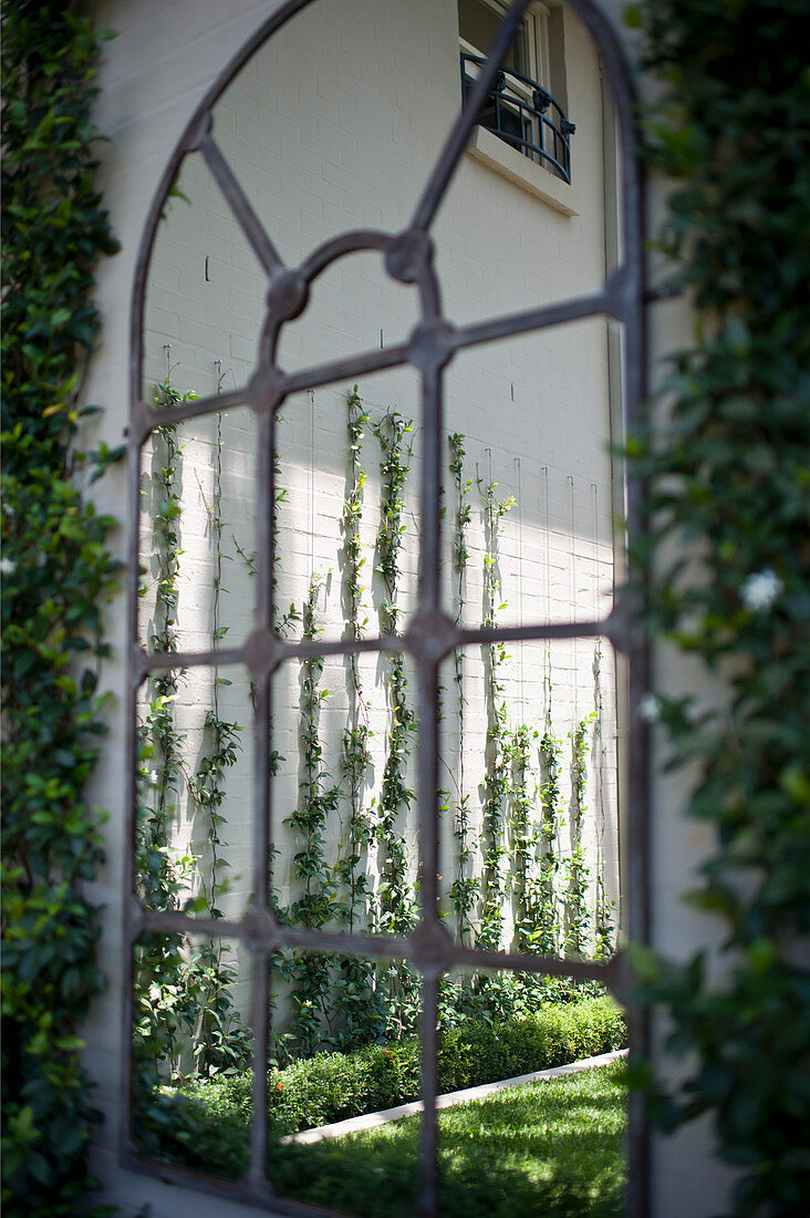 Eisenfenster mit Rundbogen in Gartenmauer