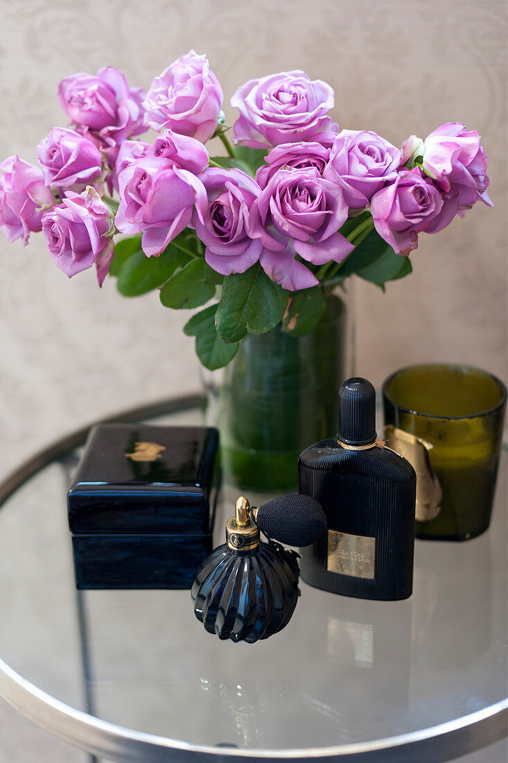 Lila Rosen in Vase, Parfum und Schmuckkästchen auf Beistelltisch