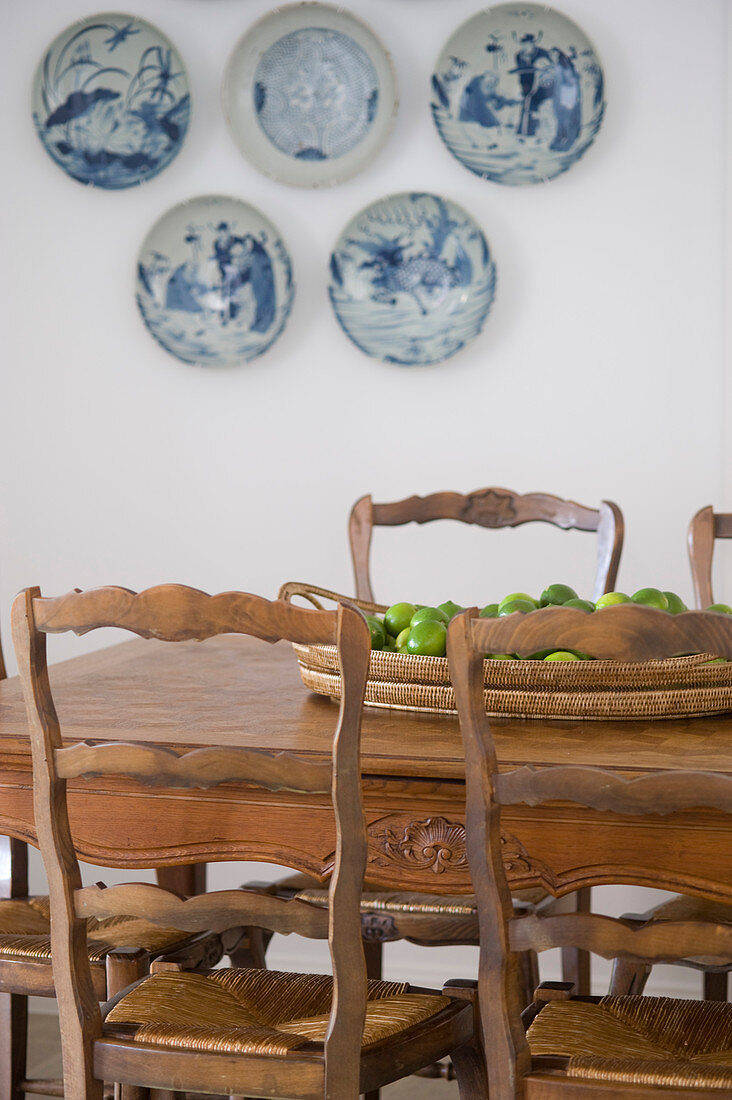 Rustikaler Holztisch mit Stühlen vor weißer Wand mit Dekotellern