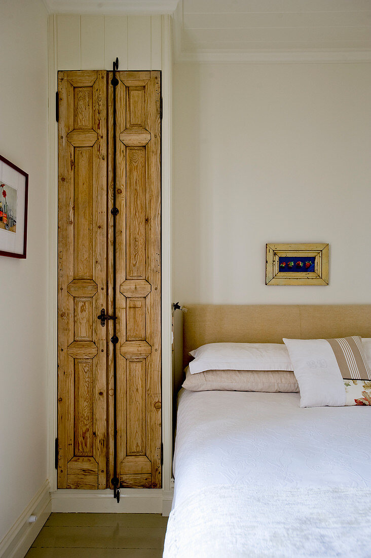 Fitted wardrobe with rustic wooden door in simple bedroom