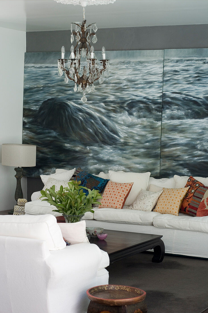 Scatter cushions on white sofa against maritime mural wallpaper
