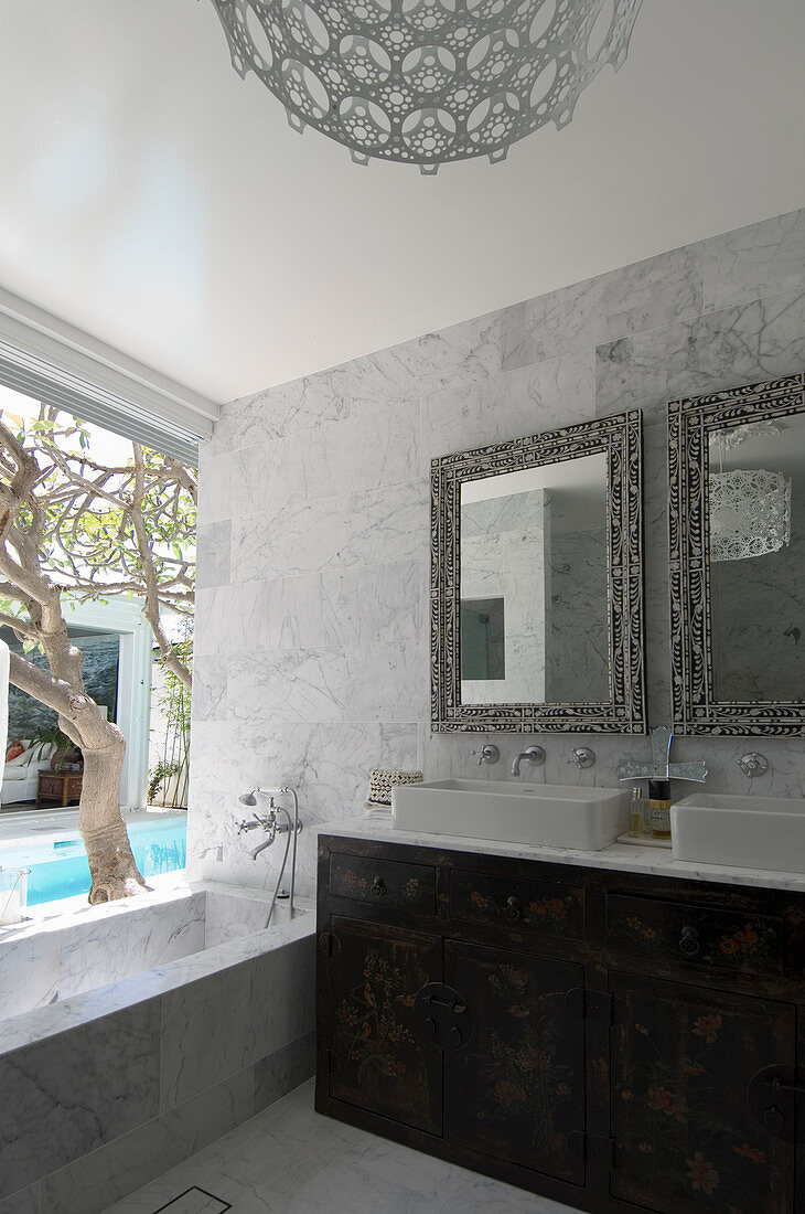 Mirrors above twin sinks and bathtub next to window