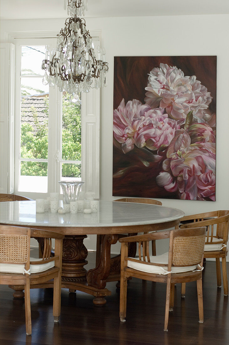 Tisch mit Marmorplatte und Stühlen vor Bild mit Blumenmotiv im Essbereich