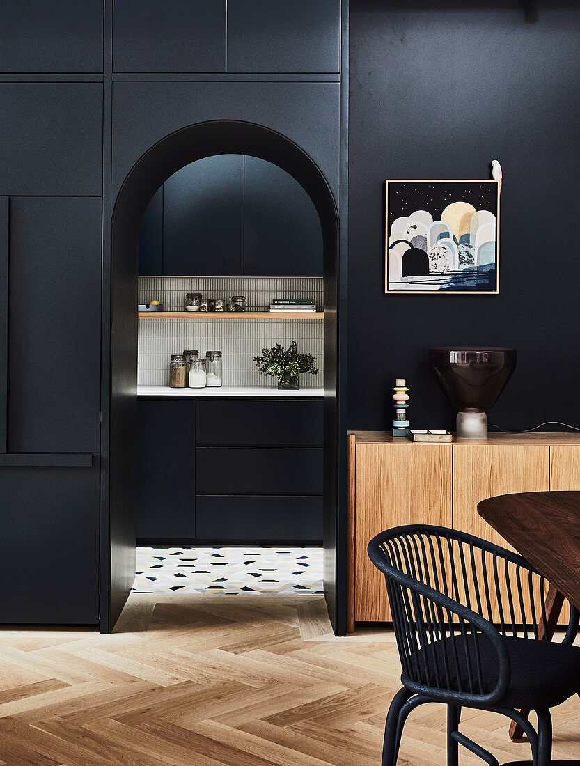 Schwarze Einbauten und Rundbogen-Ausschnitt mit Blick in die Küche