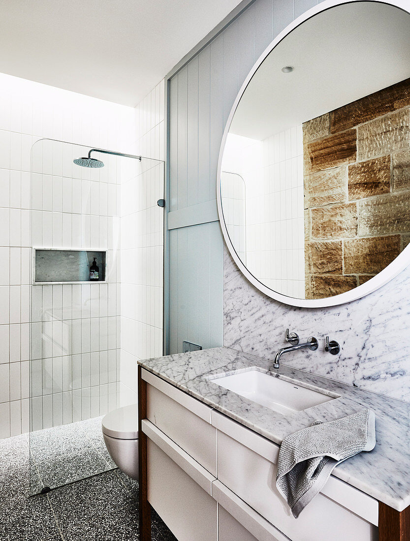 Runder Spiegel über Waschtisch mit Marmorplatte im Badezimmer