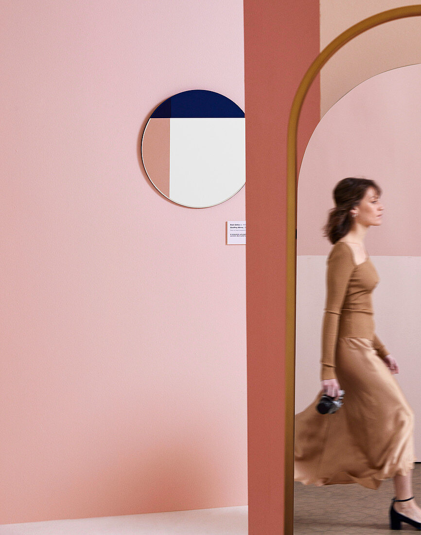 Runder Spiegel an rosa Wand, Spiegelbild von Frau in ovalem Spiegel