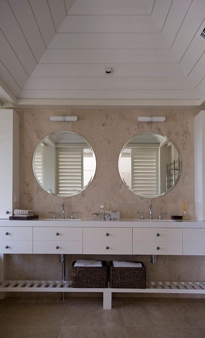 Doppelwaschbecken mit runden Spiegeln und weißen Unterschränken in Strandhaus