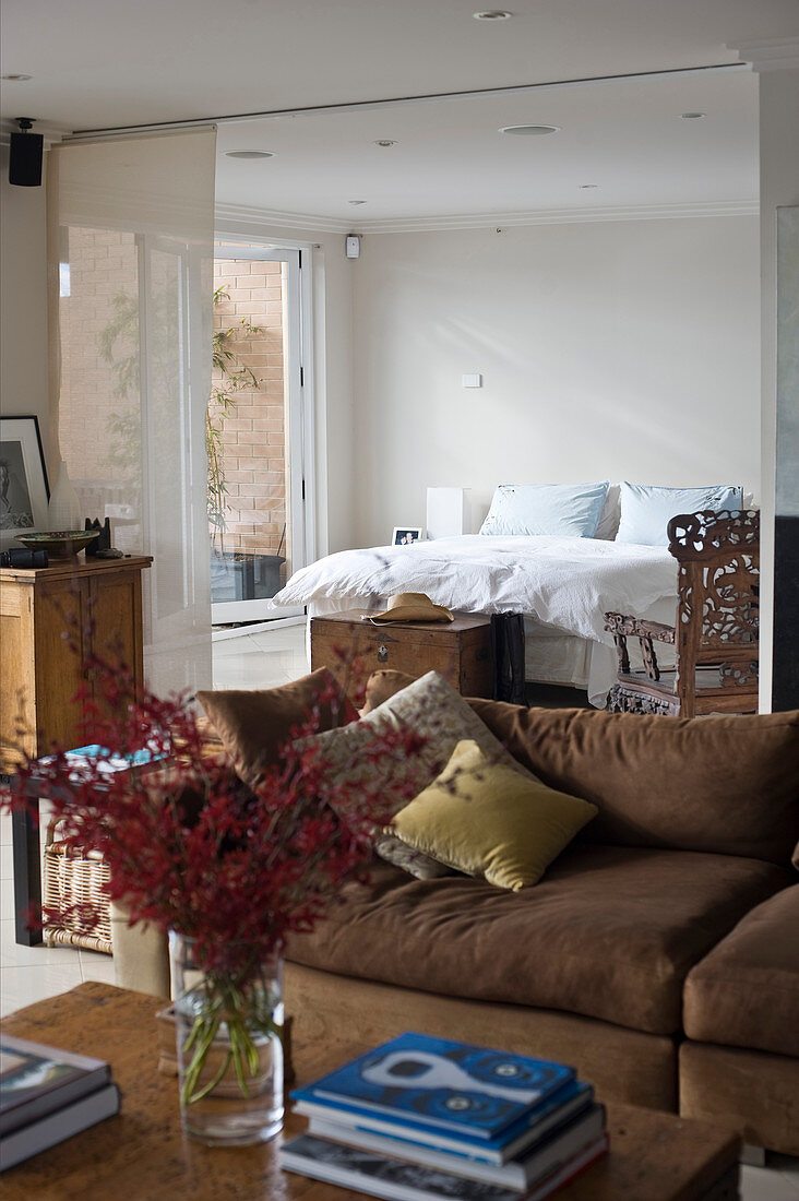 Wohnraum mit brauner Polstergarnitur und durch Vorhang abgetrenntem Schlafbereich im Hintergrund