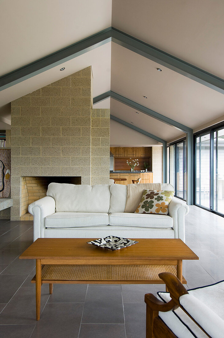 Fireplace in open-plan interior below gable roof with exposed steel beams